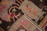 Khotan carpet folded to reveal chocolate brown pile, visible wear, and woven foundation.