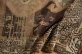 Folded vintage distressed Hamadan rug showing abrashed field and geometric border detail.