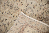 Distressed ivory pile with terracotta floral vinery, folded to reveal hand-knotted Sparta foundation.