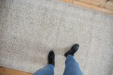 Faded ivory and beige scrolling vinery pattern on a distressed vintage Sparta rug.
