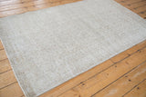 Faded ivory and beige scrolling vinery pattern with textural pile wear on this distressed Sparta rug.