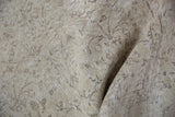 Close-up of distressed vintage Sparta rug showing faded scrolling vinery in ivory, beige, and silver.