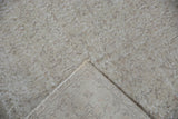 Distressed vintage Sparta rug pile with faded scrolling vinery, showing exposed foundation.