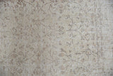 Distressed Sparta rug close-up, revealing worn vinery pattern in subtle ivory and beige tones.