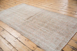 Textured wear across a distressed vintage Sparta runner in dusty blush, silver, and ivory tones.