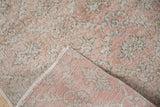 Folded corner of a distressed Sparta rug showing its low pile and hand-knotted foundation.