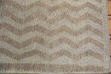 Distressed ivory and beige chevron pattern on a hand-knotted Tulu rug corner.