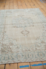 Worn ivory and pale blue abrashed field and scrolling vinery of a vintage Sparta rug.