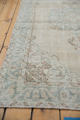 Distressed vintage Sparta rug detail: faded pale blue border, ivory field, subtle scrolling vinery.