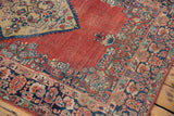 Arak rug's navy border with meandering floral vines, abrashed brick red field, and wear.