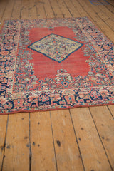Vintage Sarouk rug's navy border with floral vines, brick red field, time-softened pile.
