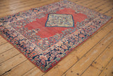 Vintage Arak rug corner with navy blue floral border, worn brick red field, and intact selvage.