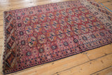 Detail of vintage Turkmen rug showing geometric magenta and navy borders with chestnut guls.