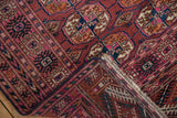 Vintage Turkmen rug corner revealing hand-knotted back, white fringe, and blue side cord.