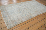 Distressed Sparta rug corner, faded scrolling vinery, soft blue, and textured pile.