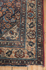 Malayer rug corner showing intricate geometric border and short fringe in navy, red, ivory.