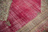 Distressed raspberry red field and serrated beige contour of a vintage Doroksh carpet.