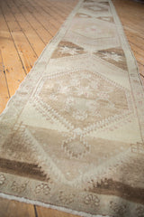 Distressed Oushak runner with oversized repeating medallions, faded ivory and brown tones.