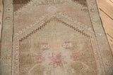 Distressed vintage Oushak runner, highlighting faded mauve starburst motif and low pile.