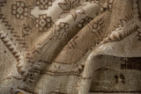 Folded vintage distressed Oushak rug runner, showing worn pile texture in browns and ivory.