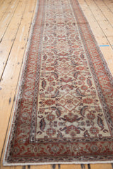 Distressed vintage Kaisery runner rug displaying ivory Herati pattern and traditional cherry red border.