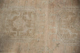 Distressed vintage Oushak rug pile texture showing subtle medallion design, faint foundation, beige, and pale copper.