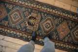 A view down the length of a vintage Karaja runner with geometric medallions in dusty teal and rust.