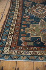 A vintage Persian Karaja rug's triple border with meandering vines in teal and terracotta.