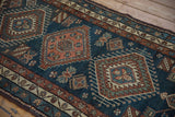 Detailed view of geometric medallions and vine border in dusty teal and terracotta.