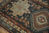 Geometric motifs and stylized human figures on a vintage Karaja rug in dusty teal and rust.