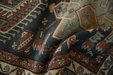 A folded view of a Karaja rug showing the low pile and geometric motifs in dusty teal and terracotta.