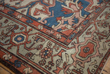 Distressed vintage Serapi rug, showcasing geometric Samovar turtle border in rust, blue, and ivory.