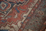 Distressed vintage Serapi pile texture with terracotta, blue, and beige meandering vine patterns.