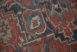 Distressed Serapi rug showing serrated geometric motifs in rust, navy, and beige tones.