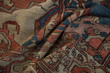 Distressed vintage Serapi carpet pile showing rust, blue, and beige geometric motifs.