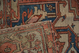 Faint foundation showing through distressed rust, blue, and beige geometric patterns on a vintage Serapi rug.