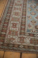 Distressed Caucasian runner showing faded geometric floral patterns and crab style border.