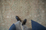 Distressed vintage Bijar carpet showing faded dusty rose, pale teal floral designs and even wear.