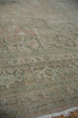 Distressed pile texture of a vintage Bijar carpet, showcasing muted pale teal and rose tones.