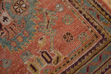 Textured distressed Oushak rug detail with ruby red field and pale blue, gold zig-zag border.
