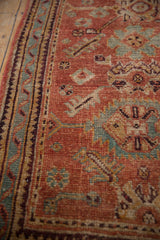 Distressed vintage Oushak rug detail showing ruby red field, pale blue blossoms, and aubergine zig-zag border.