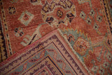 Distressed Oushak rug's folded corner showing muted pile, foundation, and detailed border pattern.