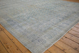Distressed vintage Meshed carpet showing worn pale blue paisley patterns and exposed foundation.