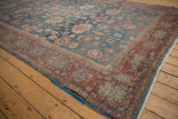 Distressed Mahal carpet corner showing faded denim blue floral field, brick red border, and fringe.