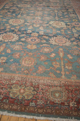 Distressed vintage Mahal carpet with denim blue field, floral palmettes, and brick red border.
