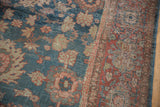 Textural detail of vintage distressed Mahal rug, faded denim blue with worn floral palmettes and brick red border.