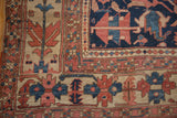 Corner of antique Heriz carpet, showing primitive brick red, navy, and ivory floral motifs.