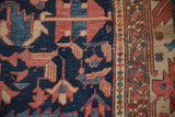 Serrated leaves, stylized birds on an antique Heriz rug with navy, brick red, ivory tones.