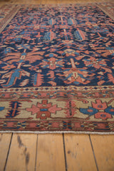Secured ivory fringe and brick red, navy geometric border of the antique Heriz carpet.