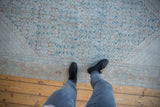 Faded dusty teal, beige, and brick red geometric pattern on a distressed Mahal carpet.